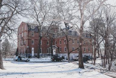 盖洛德大厅的图片，一座粉红色砖砌成的庄严建筑，坐落在雪景中.